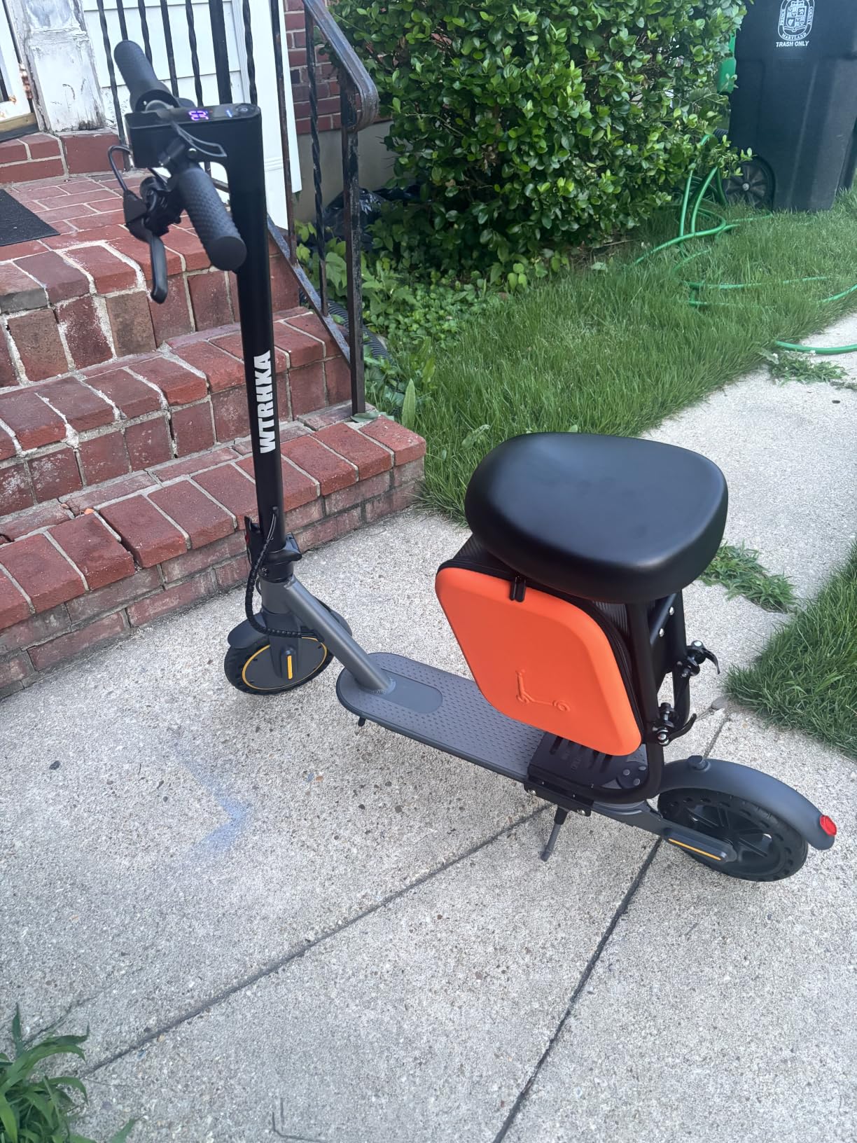 WTRHXA W2 with a black seat and orange storage bag parked on a sidewalk next to brick front steps
