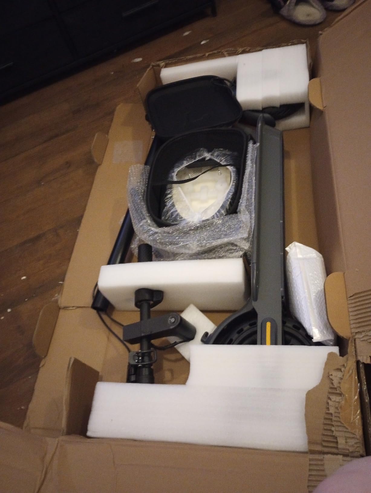 Folded WTRHXA scooter still in its shipping box with foam blocks and the wrapped seat bag